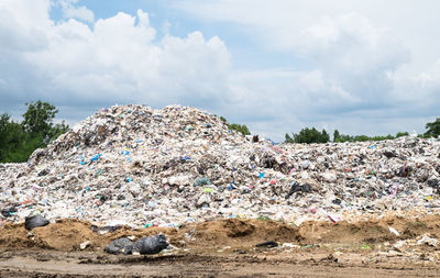 Stack of garbage on land against sky