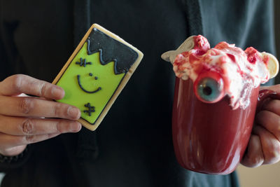Close-up of person holding monster cookie and halloween drink