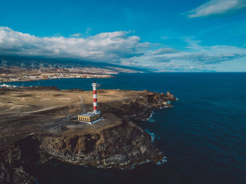 Lighthouse by sea against sky