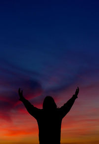 Silhouette woman standing against orange sky