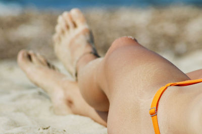 Low section of woman in bikini at beach