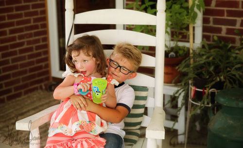 Siblings sitting on chair at yard