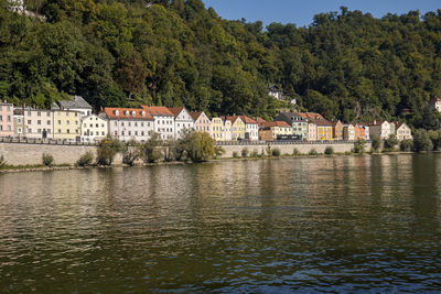 Houses by river amidst trees and buildings in city