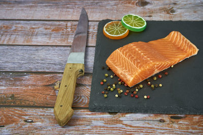 Fresh salmon fillets on black cutting board with herbs and spice