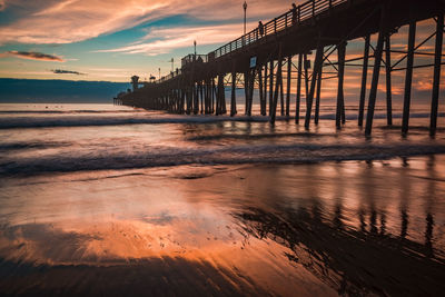 Pier over sea against sky during sunset