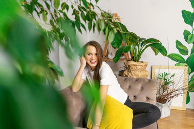 Happy young woman sitting on potted plant