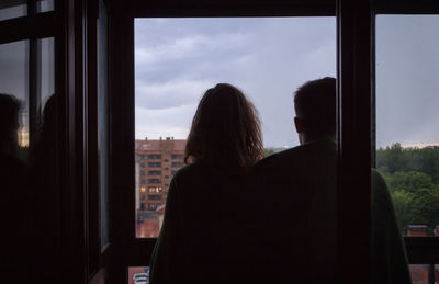 Rear view of man and woman looking through window