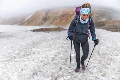Female backpacker hiking snow on laugavegur trail near landmannalaugar