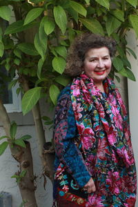 Portrait of smiling young woman standing against plants