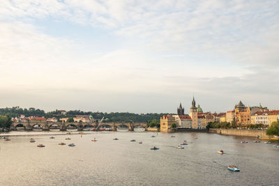 View of buildings by river against cloudy sky