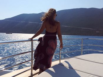 Full length of young woman standing on boat sailing in sea