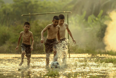 Full length of shirtless boy splashing water