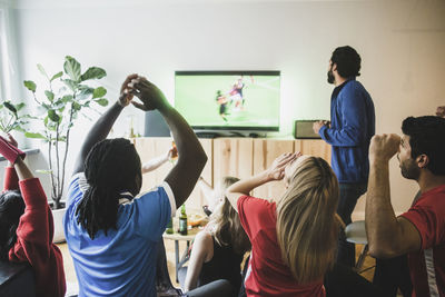 Fans cheering while watching soccer match on tv at home
