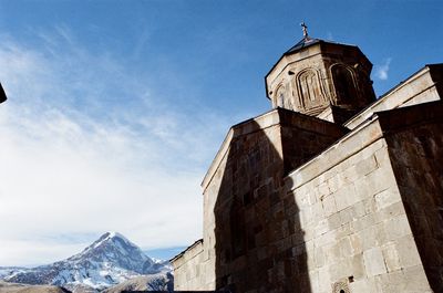 28mm angle view of gergeti trinity church against sky and glacier . 35mm ektar