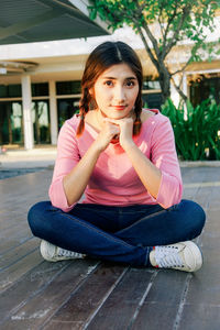 Portrait of woman with pigtail sitting on floorboard