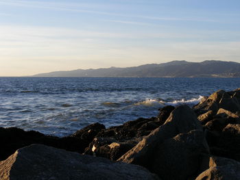 Scenic view of sea and rocky shore against sky