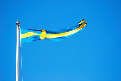 Low angle view of swedish flag against clear blue sky