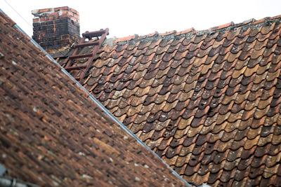 Low angle view of brick wall by building against sky