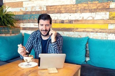 Portrait of young man sitting on table at cafe