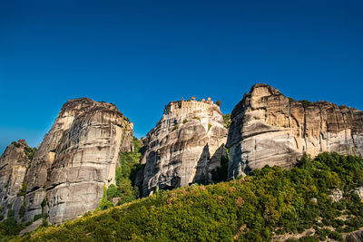 Low angle view of rocks against clear blue sky