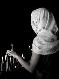 Close-up of hands against illuminated light over black background