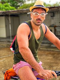 Midsection of man wearing hat sitting outdoors