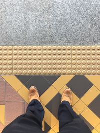 Low section of man standing on tiled floor