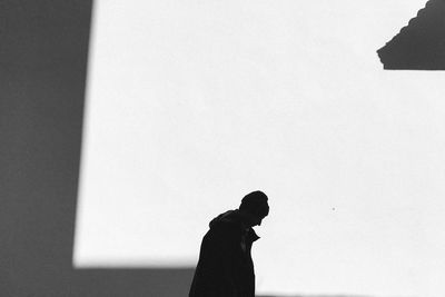 Silhouette man standing against wall