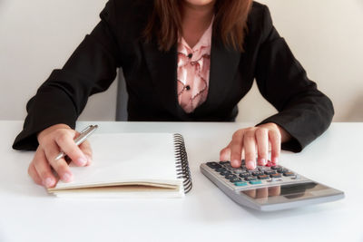 Midsection of woman reading book on table