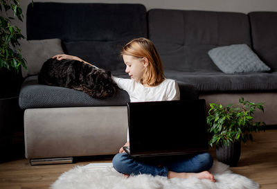 Woman using laptop while sitting on sofa at home