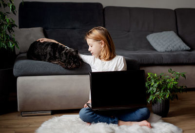 Girl using laptop while sitting on sofa at home