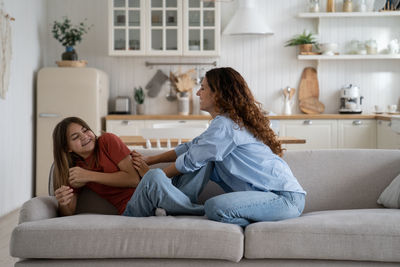 Happy positive mother spending leisure carefree time with her teenage daughter, having fun at home