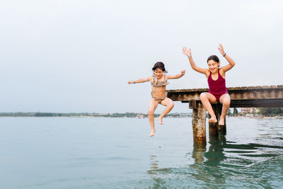 Two children jumping from the bridge in the water