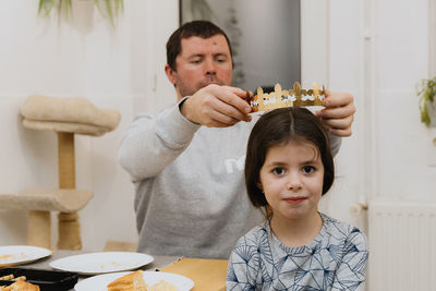 A young man puts a crown on a girl after eating a royal galette.