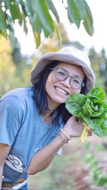 Portrait of smiling young woman holding plant