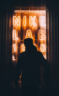 Rear view of man standing in illuminated building