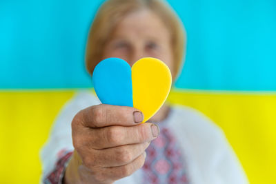 Woman holding heart shape candy against ukrainian flag