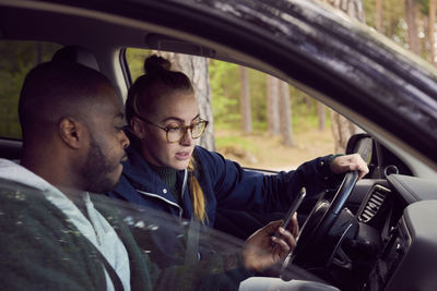 Man showing mobile phone to woman while sitting in car