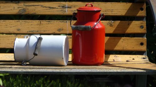 Close-up of milk canisters on wooden bench