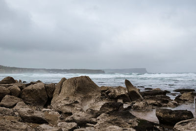 Rocks on beach against sky