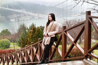Portrait of young woman standing on stairs with bridge view