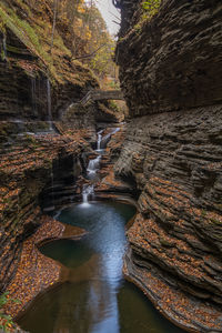 Waterfalls in a sculpted rocky gorge with a stone bridge in the autumn