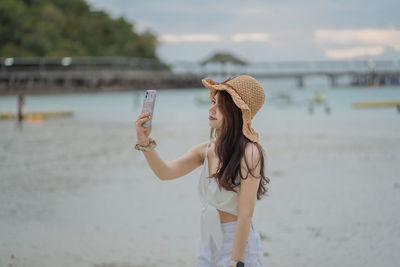 Woman wearing hat while standing on beach