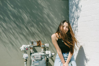 Portrait of young woman standing against wall