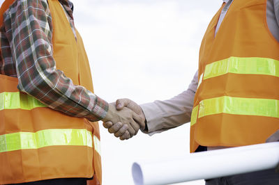 Low angle view of men working against sky