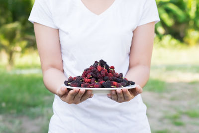 Midsection of woman holding berry fruits in plate