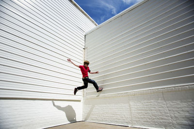 Low angle view of man jumping on white wall