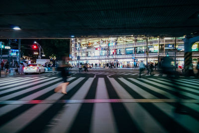 People walking on illuminated street in city