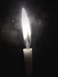 Close-up of burning candle against black background