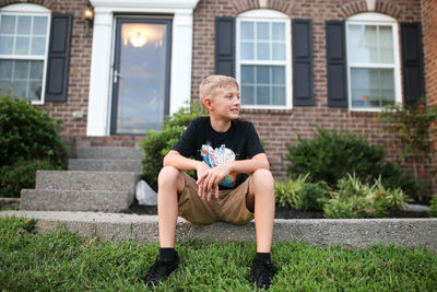 Full length of boy sitting outside house